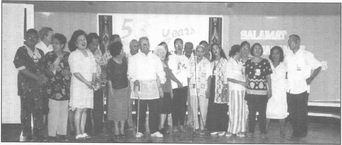 Line of pioneers standing on a stage in front of a banner reading 50 Years.