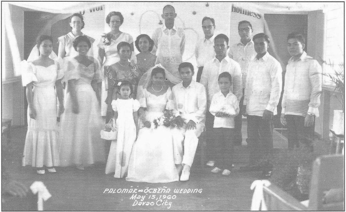 Wedding party posed inside a church, bride in white seated at the centre.