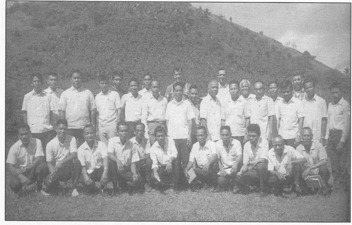 Rows of pastors standing together on a grassy slope for a conference portrait.