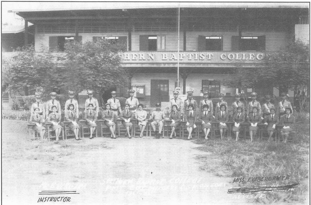 Long row of students seated outside the Southern Baptist College building with an instructor.
