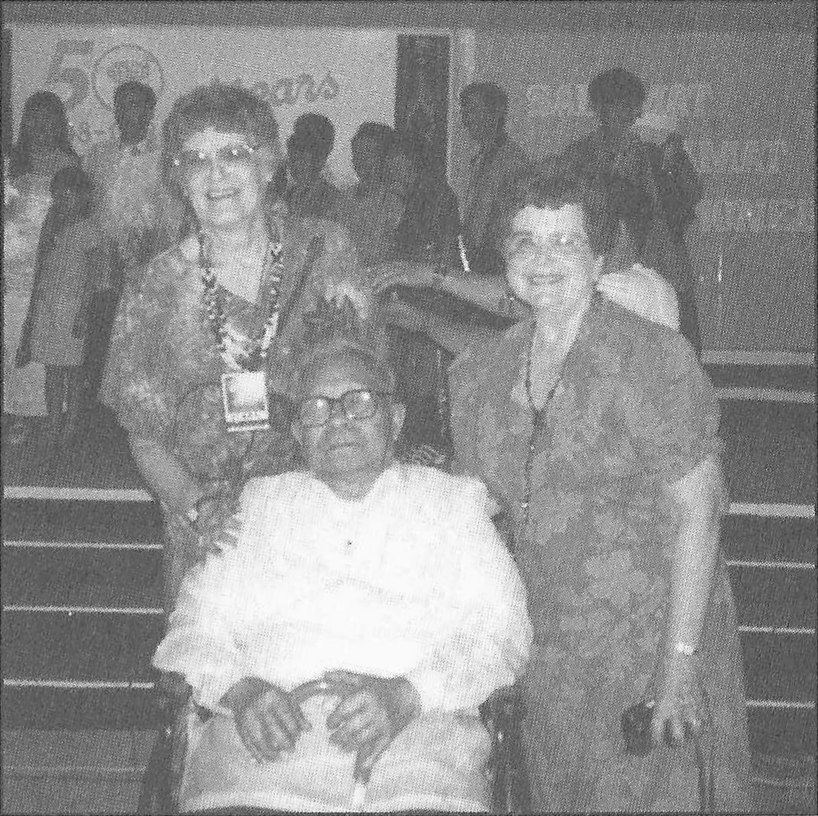 The writer seated between two women at the fiftieth anniversary celebration.